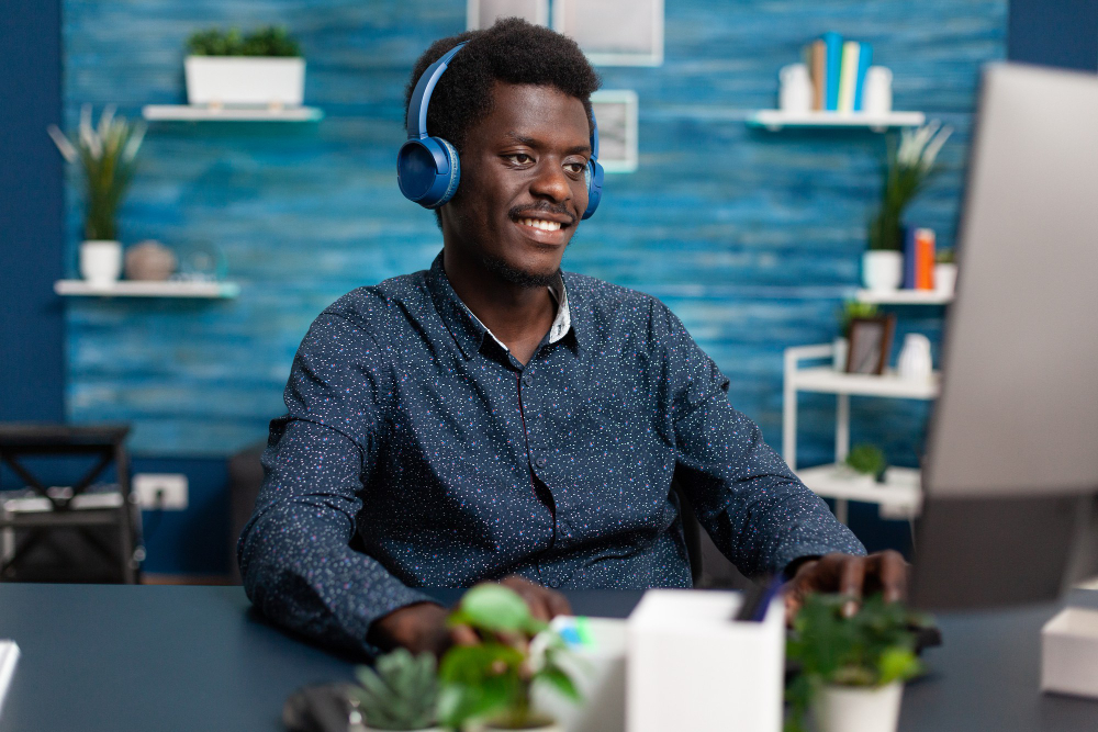 authentic-smiling-african-american-man-using-laptop-headphones-work-from-home-learn-freel